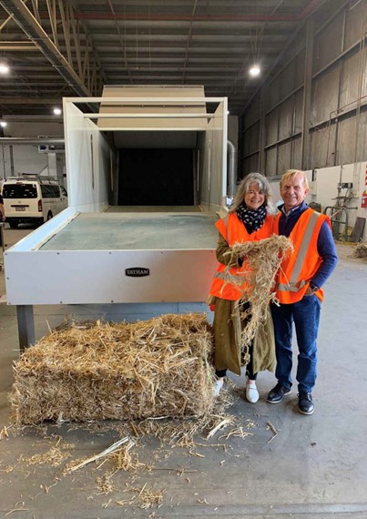 Hemp Pioneers Dave & Anne Jordan standing in front of their decortication machine inside their huge hemp fibre factory, near Christchurch